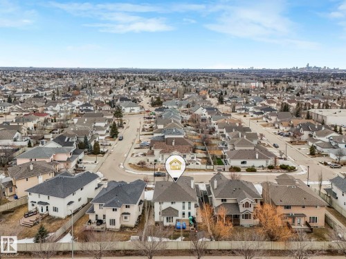 Aerial view of the property and surrounding neighborhood, featuring residential homes with pitched roofs and a distant city skyline - 1147 Lincoln Crescent, Edmonton, AB - Outdoor With View