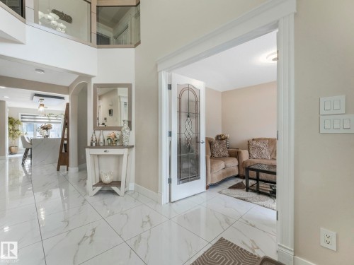 The property features a bright entryway with polished tile flooring, a decorative console table with a mirror, and a view into a living area - 1147 Lincoln Crescent, Edmonton, AB - Indoor Photo Showing Other Room