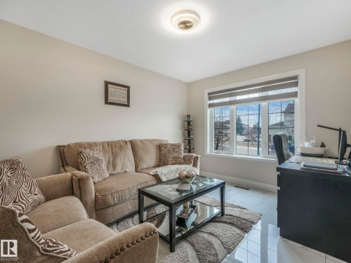 This inviting living space features light-colored walls, a prominent window with blinds, and polished tile flooring - 1147 Lincoln Crescent, Edmonton, AB - Indoor Photo Showing Living Room