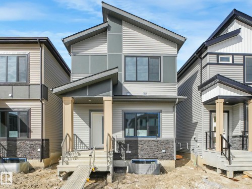 The property features a modern exterior with varied siding, a striking roofline, and a prominent front entrance with columns - 275 Munn Way, Leduc, AB - Outdoor