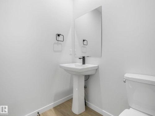 Bathroom with a white pedestal sink, a rectangular mirror, and a modern black faucet - 275 Munn Way, Leduc, AB - Indoor Photo Showing Bathroom