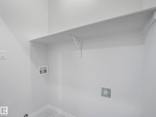 Utility room featuring a wall-mounted shelf, electrical outlets, and plumbing hookups - 275 Munn Way, Leduc, AB - Indoor