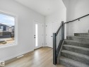 Entryway featuring light-toned flooring, a white paneled door with a vertical frosted glass insert, and a staircase with grey carpet and a dark banister - 275 Munn Way, Leduc, AB  - Indoor Photo Showing Other Room 