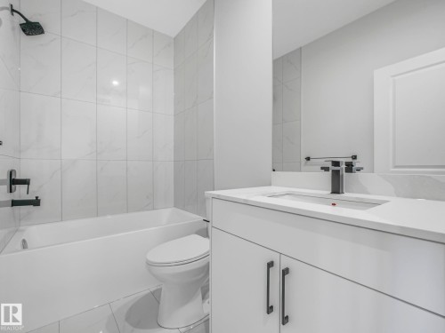The bathroom features a modern vanity with a rectangular sink, a black faucet, and a large mirror - 275 Munn Way, Leduc, AB - Indoor Photo Showing Bathroom