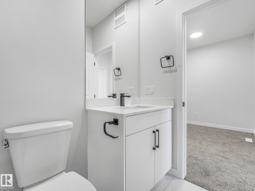 Bathroom with a white vanity featuring a sink, black faucet, and black cabinet hardware - 275 Munn Way, Leduc, AB - Indoor Photo Showing Bathroom