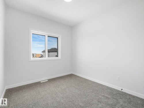 This room features light grey walls, grey carpet, and a window providing natural light - 275 Munn Way, Leduc, AB - Indoor Photo Showing Other Room