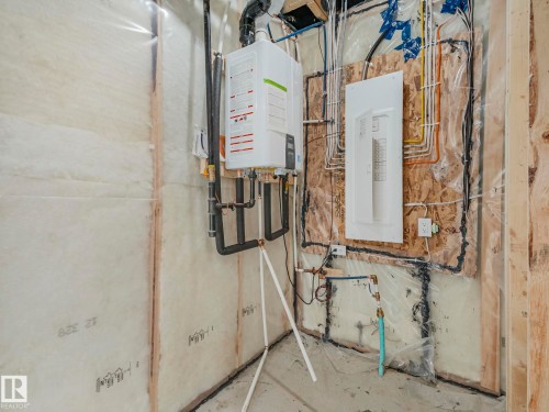 The property features a tankless water heater, an electrical panel, and exposed wall insulation - 275 Munn Way, Leduc, AB - Indoor Photo Showing Basement