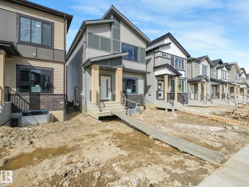 This property features a contemporary design with neutral-toned siding, dark trim, and a prominent front entrance with a covered porch and railings - 275 Munn Way, Leduc, AB - Outdoor With Facade