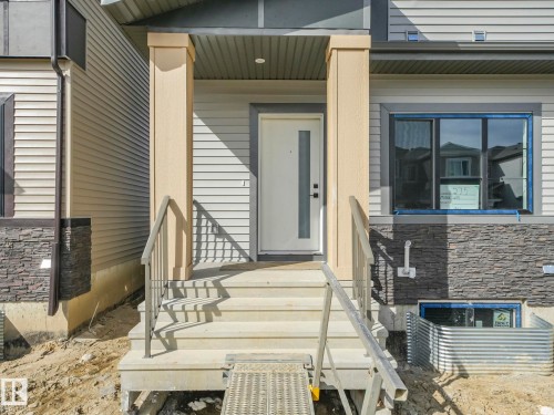 The property features an entryway with concrete steps, metal railings, and a prominent front door with a vertical glass insert - 275 Munn Way, Leduc, AB - Outdoor
