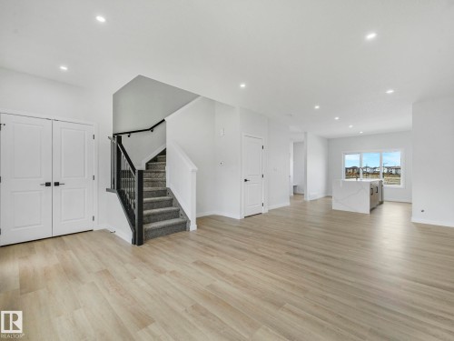 This open-concept living area features light-toned flooring, white walls, and recessed lighting - 275 Munn Way, Leduc, AB - Indoor