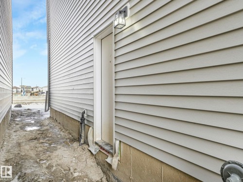 The property features light-colored horizontal siding and a foundation with visible concrete - 275 Munn Way, Leduc, AB - Outdoor