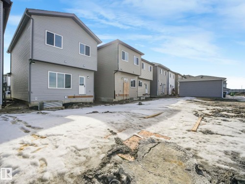 The property features a two-story exterior with light gray siding and a white door, complemented by white-framed windows - 275 Munn Way, Leduc, AB - Outdoor