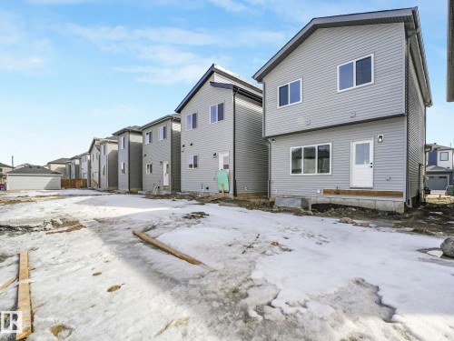 The property features a two-story exterior with light gray siding and a dark roof, along with multiple windows providing natural light - 275 Munn Way, Leduc, AB - Outdoor