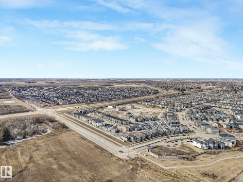 Aerial view showcasing the expansive residential area with a variety of homes, paved roadways, and surrounding open land - 275 Munn Way, Leduc, AB - Outdoor With View