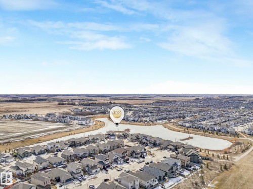 Aerial view showcasing the surrounding residential area with numerous detached properties, a nearby body of water, and extensive open fields in the background - 275 Munn Way, Leduc, AB - Outdoor With View