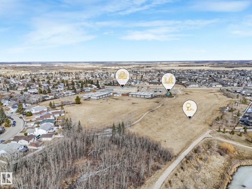 Aerial view of the property's surrounding area, featuring residential developments, open fields, and a body of water - 275 Munn Way, Leduc, AB - Outdoor With View