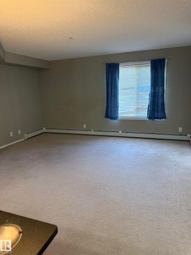 Spacious room featuring carpeting, neutral-toned walls, and a window providing natural light - 104 3207 James Mowatt Trail, Edmonton, AB - Indoor Photo Showing Other Room