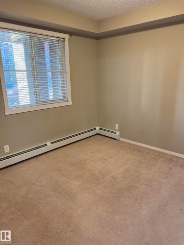 This room features a window with blinds, baseboard heating, and carpeting - 104 3207 James Mowatt Trail, Edmonton, AB - Indoor Photo Showing Other Room