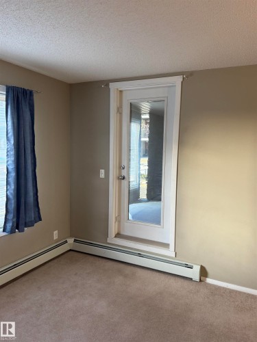 The room features carpeting, neutral-toned walls, and baseboard heating - 104 3207 James Mowatt Trail, Edmonton, AB - Indoor Photo Showing Other Room