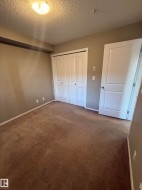 This room features a brown carpeted floor, light taupe walls, and a white bi-fold closet door - 