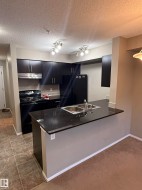 The kitchen features dark cabinetry, black appliances, and a double-basin sink - 
