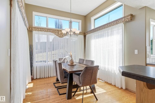 Dining area featuring hardwood floors, high ceilings, large windows with decorative valances, and a chandelier - 442 Hunters Green, Edmonton, AB - Indoor Photo Showing Dining Room