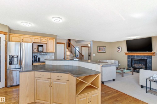 The property features an open concept kitchen and living area, complete with a fireplace and wood floors - 442 Hunters Green, Edmonton, AB - Indoor Photo Showing Kitchen With Fireplace