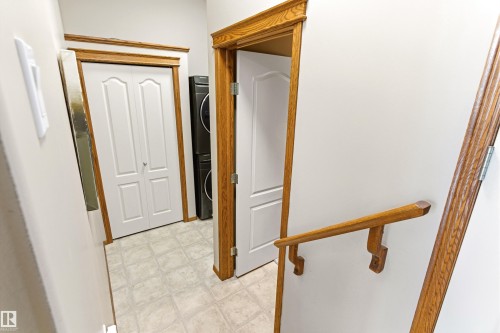 This area features light-colored walls, wood trim around doorways, and a wood handrail - 442 Hunters Green, Edmonton, AB - Indoor Photo Showing Other Room