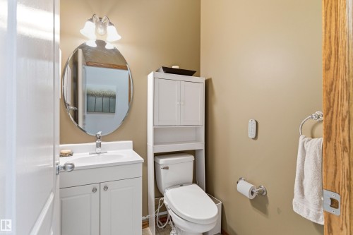 This bathroom features a white vanity with a single sink and a framed oval mirror - 442 Hunters Green, Edmonton, AB - Indoor Photo Showing Bathroom