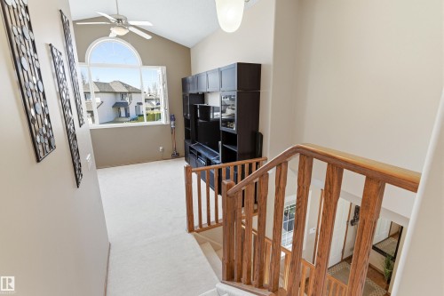 This bright interior space features a vaulted ceiling with a ceiling fan, a large arch-top window, and carpeted flooring - 442 Hunters Green, Edmonton, AB - Indoor Photo Showing Other Room