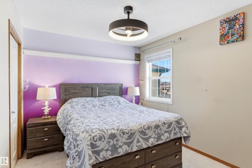 The property features a bedroom with a window providing natural light, a ceiling fan with integrated lighting, and a neutral wall color complemented by a vibrant accent wall - 442 Hunters Green, Edmonton, AB - Indoor Photo Showing Bedroom