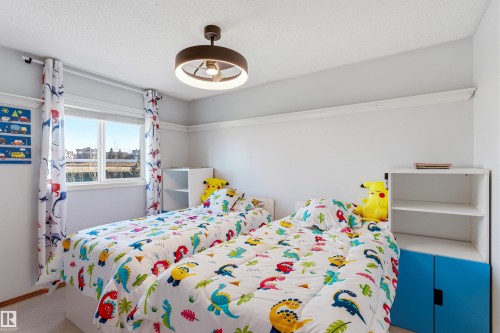 Bright room featuring a window with white blinds, a ceiling-mounted light fixture, and shelving units with blue cabinet doors - 442 Hunters Green, Edmonton, AB - Indoor Photo Showing Bedroom