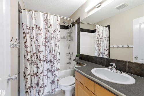 Bathroom featuring a vanity with an integrated sink, a large mirror, and a shower-over-bath with a shower curtain - 442 Hunters Green, Edmonton, AB - Indoor Photo Showing Bathroom