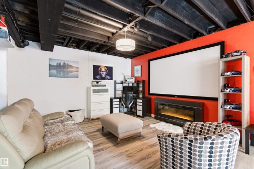 Entertainment space featuring a large projection screen, an electric fireplace, and light-toned flooring - 442 Hunters Green, Edmonton, AB - Indoor With Fireplace