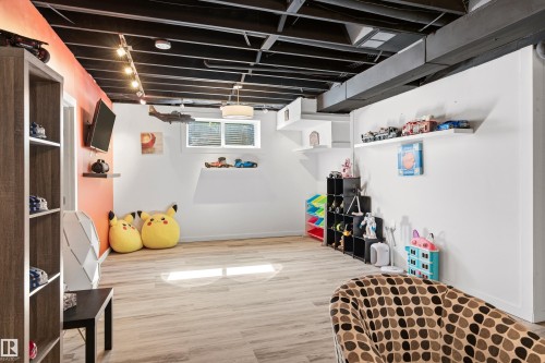This spacious room features light-toned flooring, white walls, and a ceiling with exposed, painted beams - 442 Hunters Green, Edmonton, AB - Indoor Photo Showing Basement