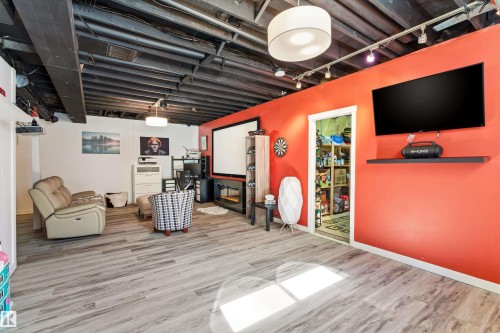 This versatile space features light-toned flooring, exposed dark ceiling beams, and a brightly painted accent wall - 442 Hunters Green, Edmonton, AB - Indoor