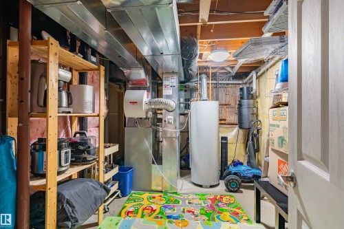 The unfinished basement features exposed ceiling beams, a water heater, and a furnace - 442 Hunters Green, Edmonton, AB - Indoor Photo Showing Basement