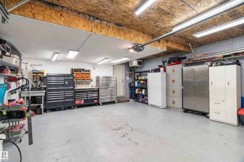 The property features a garage with a light-colored floor, overhead lighting, and exposed wood ceiling joists - 442 Hunters Green, Edmonton, AB - Indoor Photo Showing Garage