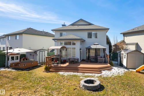 The property features a spacious backyard with a large wooden deck and a fire pit - 442 Hunters Green, Edmonton, AB - Outdoor With Deck Patio Veranda