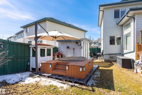 The property includes a spacious backyard featuring a raised wooden deck with integrated lighting, a hot tub, and a privacy fence - 442 Hunters Green, Edmonton, AB - Outdoor With Exterior