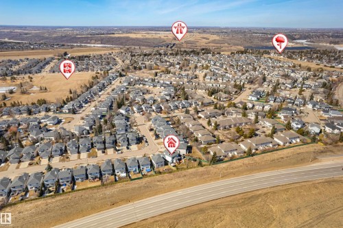 Aerial view highlighting the property within a residential community, featuring numerous homes with dark roofs and a nearby roadway - 442 Hunters Green, Edmonton, AB - Outdoor With View