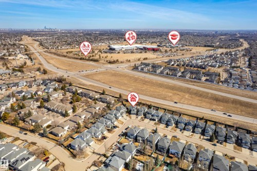 Aerial view showcasing the residential community, with a visible major roadway and distant city skyline - 442 Hunters Green, Edmonton, AB - Outdoor With View