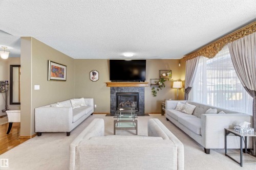 Living room with a fireplace featuring dark tile surround and a wooden mantel - 442 Hunters Green, Edmonton, AB - Indoor Photo Showing Living Room With Fireplace