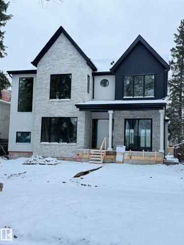 The property features a stone and stucco exterior with dark-framed windows and a covered front entrance - 10223 130 Street, Edmonton, AB - Outdoor