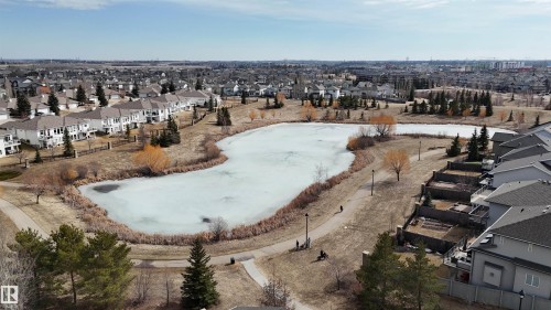 Overlooking a frozen pond, this property offers views of the surrounding neighborhood and greenspace, featuring mature trees and walking paths - 6604 Sandin Cove, Edmonton, AB - Outdoor With View