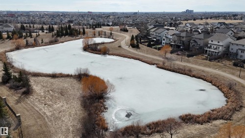 The property is situated in a community featuring a substantial pond with surrounding pathways and established trees - 6604 Sandin Cove, Edmonton, AB - Outdoor With View