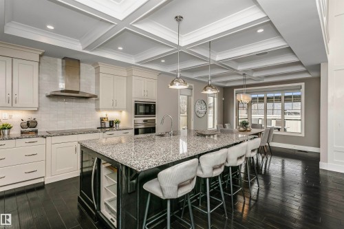 Well-appointed kitchen featuring a large island with seating, dark wood flooring, and coffered ceilings - 3435 Keswick Boulevard, Edmonton, AB 