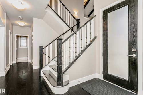 The property features a welcoming entryway with dark hardwood flooring and a stylish staircase - 3435 Keswick Boulevard, Edmonton, AB 