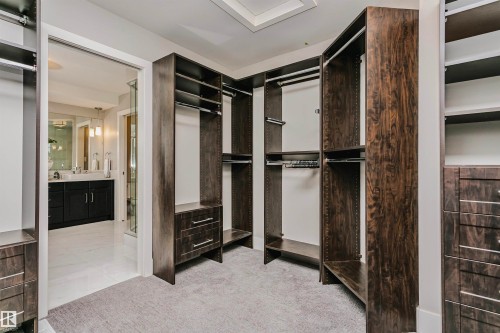 The property features a walk-in closet with extensive dark wood cabinetry, shelving, and hanging rods - 3435 Keswick Boulevard, Edmonton, AB 