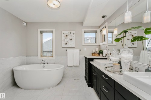 This bathroom features a freestanding soaking tub, dual vanity with undermount sinks, and windows providing natural light - 3435 Keswick Boulevard, Edmonton, AB 